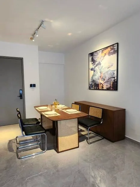 Dining features: rectangular dining table, 4 dining chairs with metal frame and cane backrest, wooden sideboard, framed artwork on wall, spotlights on ceiling, grey marble flooring, white painted walls, table settings with plates and cutlery; style: modern.